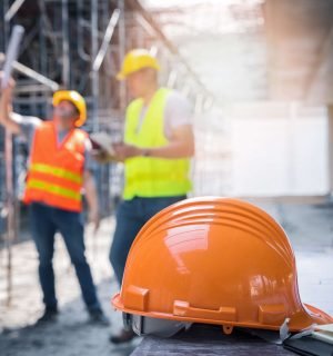 The yellow safety helmet in construction site and construction site worker background safety first concept.